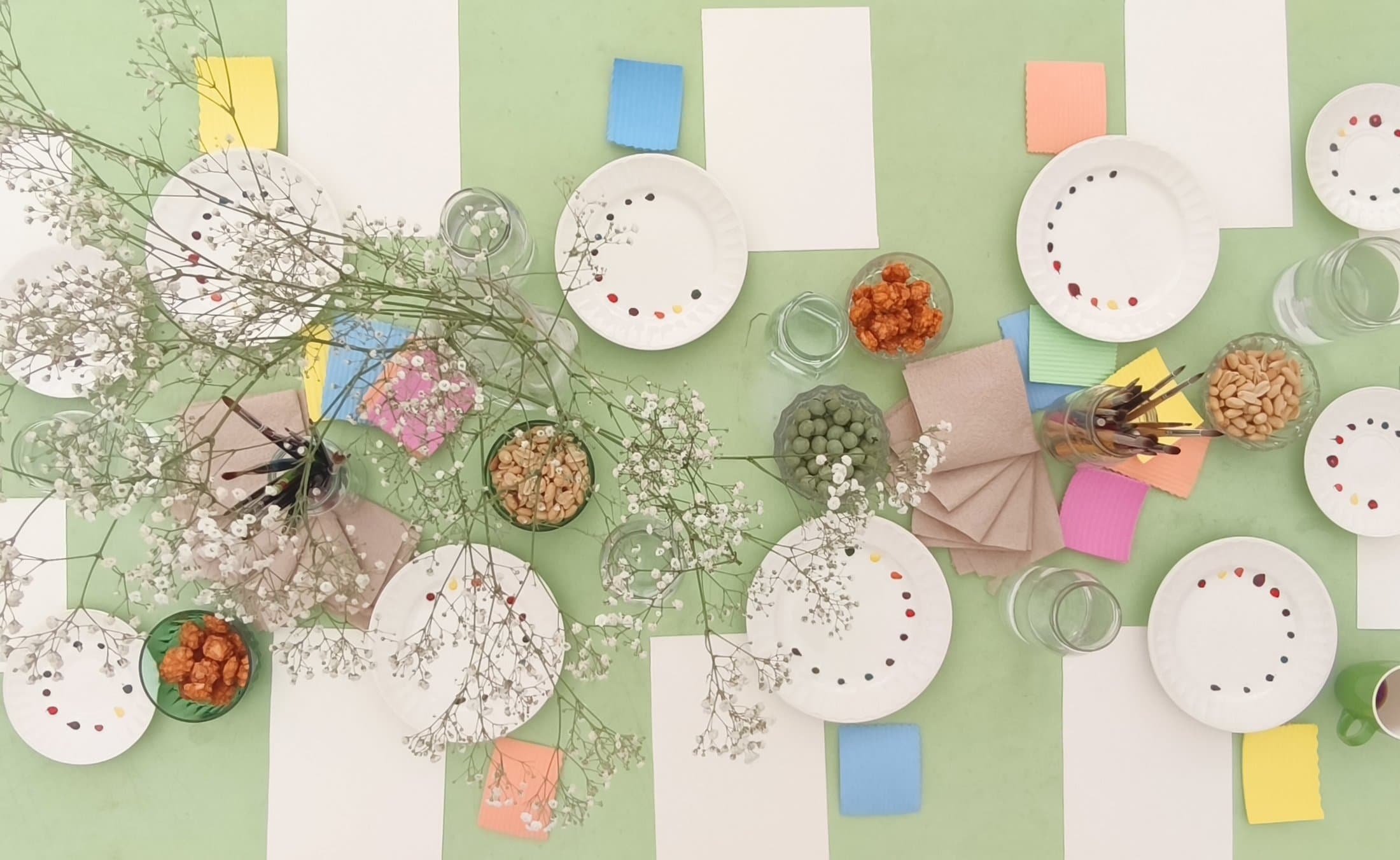 Table d'atelier aquarelle : assiettes peintes, fleurs et matériel de peinture